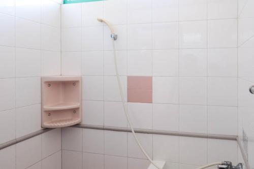 a bathroom with a urinal on a white tiled wall at RedDoorz Syariah near Kopeng Treetop Adventure in Salatiga