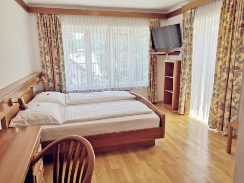 a bedroom with a bed and a table and a window at Hotel Auszeit in Sankt Kanzian