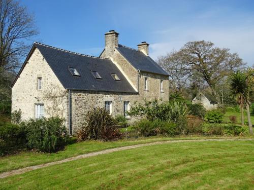 a large stone house with a black roof at Gites Du Manoir de Savigny in Valognes
