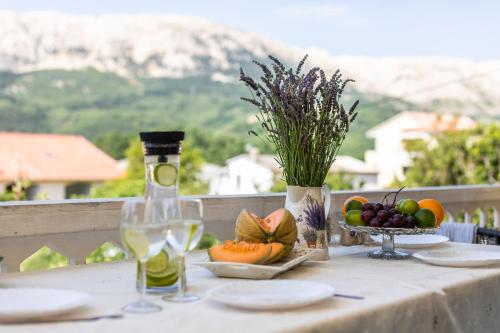 a table with a bottle of wine and a bowl of fruit at Apartments Marija in Baška