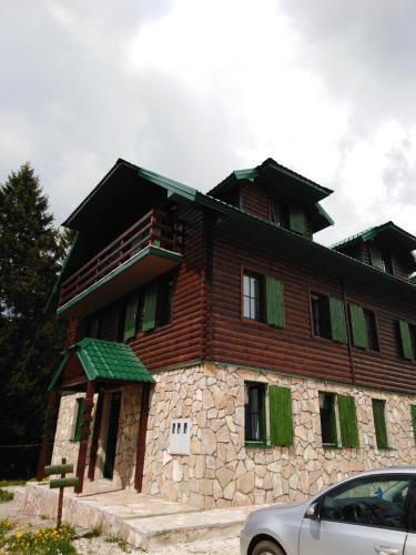 a large wooden house with a car parked in front of it at Apartments Durmitor in Žabljak