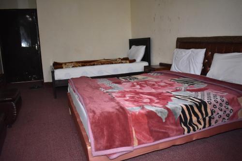 a bedroom with two beds with a red blanket at Hotel Islamabad Residency in Islamabad