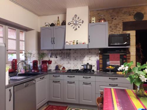 une cuisine avec des armoires blanches et un four à plaques de cuisson dans l'établissement halte aux places, à Marcillac-Saint-Quentin