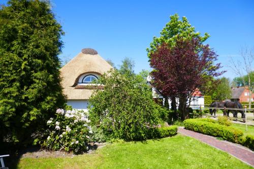 a thatched house with a horse in a yard at Refugium im Nordseewind in Norddeich