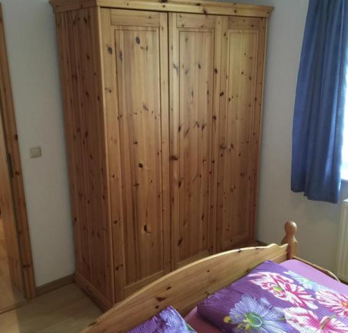 a bedroom with a wooden cabinet next to a bed at Hotel garni SEESCHLÖSSCHEN in Kolpinsee