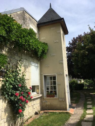Avoine的住宿－chambre sur jardin entre Fontevraud et RignyUssé，一座有窗户和玫瑰树丛的建筑