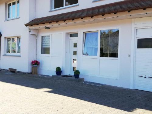 une maison blanche avec des portes blanches et des plantes en pot dans l'établissement Ferienwohnung Gudi, à Winterkasten