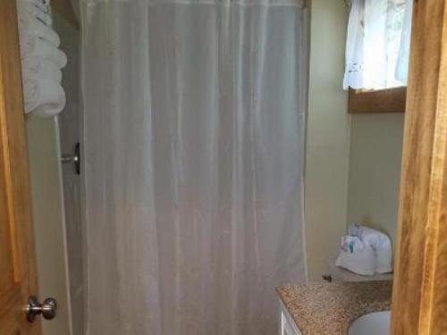a bathroom with a shower with a white shower curtain at Grand View Resort in Weirs Beach