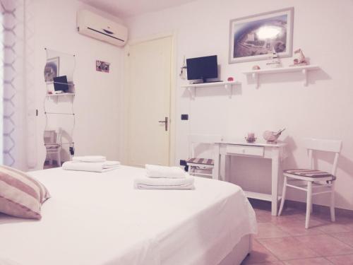 ポルト・チェザーレオにあるGiada Room Porto Cesareoの白いベッドルーム(ベッド1台、デスク付)
