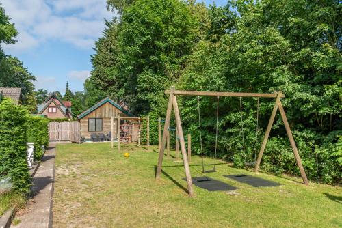 a playground with a swing set in a yard at Vakantiehuis Duin Bos en Zee in Schoorl