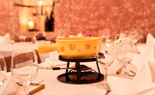 a table with a yellow pot on a stand with wine glasses at Hotel Restaurant Kreuz in Kaiserstuhl