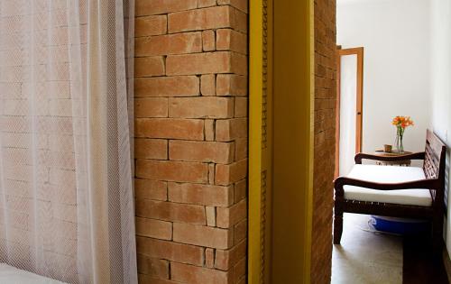 a room with a brick wall and a chair at Estalagem Camburi in Camburi