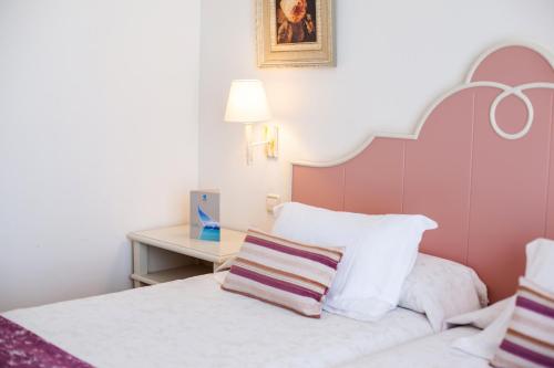 a bedroom with a bed with a pink headboard and a table at Grupotel Macarella Suites & Spa in Son Xoriguer