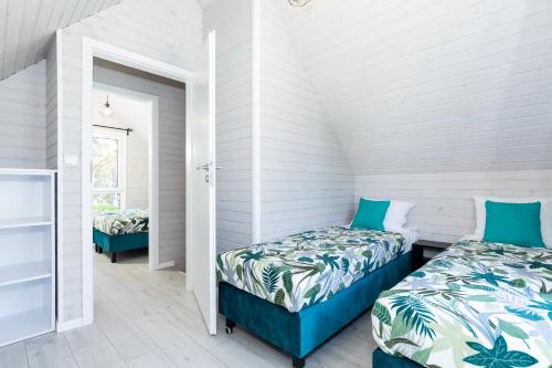 two beds in a room with white walls at Villa6 I Domki Pobierowo in Pobierowo