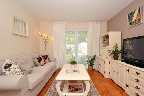 a living room with a white couch and a tv at Bora bora Apartment in Kaštela