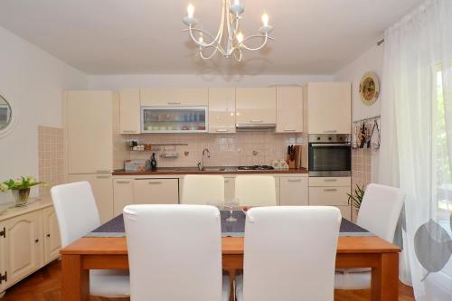 a kitchen with a table with white chairs and a chandelier at Bora bora Apartment in Kaštela