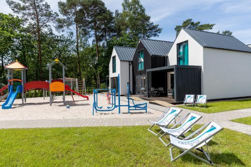 a playground with two lawn chairs and a slide at Villa6 I Domki Pobierowo in Pobierowo