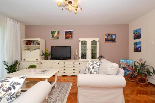 a living room with white furniture and a tv at Bora bora Apartment in Kaštela