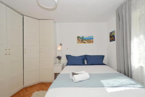 a white bedroom with a bed with blue pillows at Bora bora Apartment in Kaštela