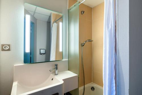 a bathroom with a sink and a mirror and a shower at B&B HOTEL Cholet Sud in Cholet