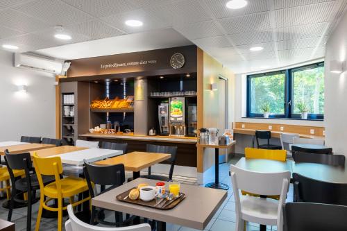 a restaurant with tables and chairs and a counter at B&B HOTEL Cholet Sud in Cholet