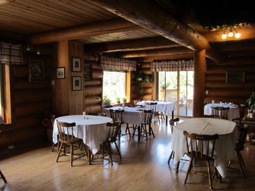 a dining room with white tables and chairs at Lac Des Roches Resort in Bridge Lake