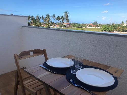 a wooden table with plates and glasses on a balcony at Vilas Blancas in Cumbuco