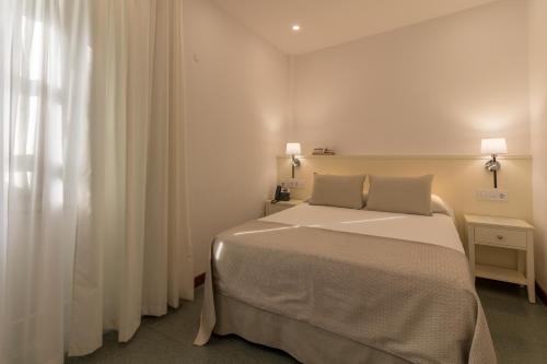 a white bedroom with a bed and a window at Hotel Emblemático Holiday Time in Santa Cruz de la Palma