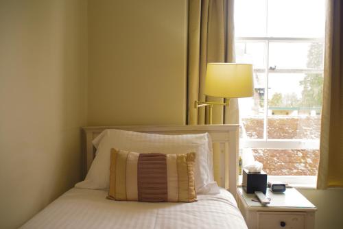a bedroom with a bed with a lamp and a window at Dene House Guest House in Bowness-on-Windermere