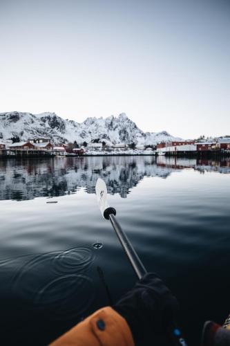a person is rowing a boat in the water at Solsiden Brygge Rorbuer in Ballstad