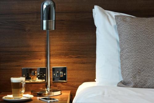 a bed with a lamp and a cup of coffee on a table at Best Western Ship Hotel in Weybridge