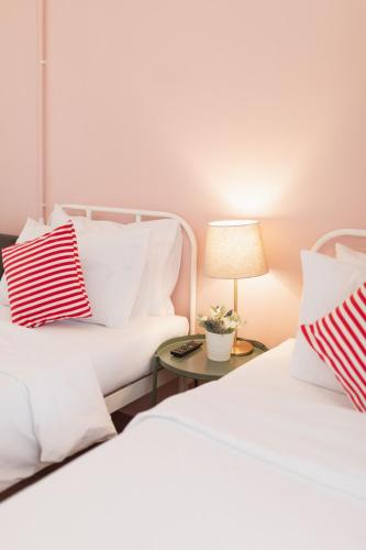 two beds with white pillows and a table with a lamp at House Of Papa Bangkok Siam in Bangkok