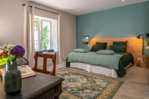 a bedroom with a bed and a table with a vase of flowers at Le Clos d'Abrigeon in Aubenas