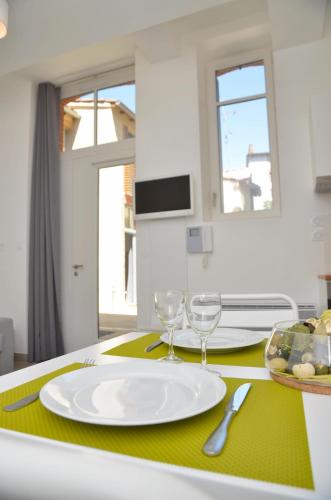 a table with a white plate and two wine glasses at Le Clos des Salins in Toulouse