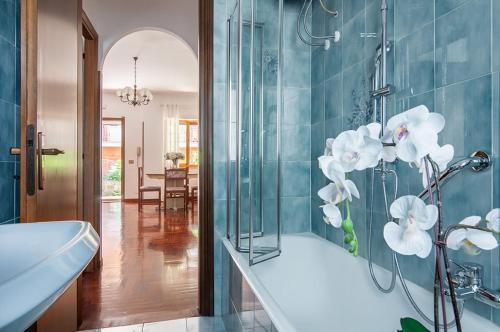 a bathroom with a tub and a shower with white flowers at Olympic Suite Roma in Rome