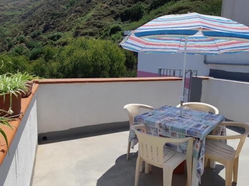a table and chairs with an umbrella on a balcony at Baia Unci in Canneto