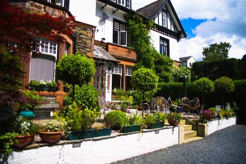 a house with a bunch of plants in front of it at Dene House Guest House in Bowness-on-Windermere