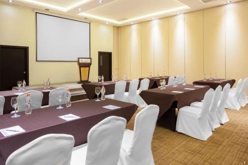a conference room with tables and white chairs and a screen at Wyndham Quito Airport in Tababela