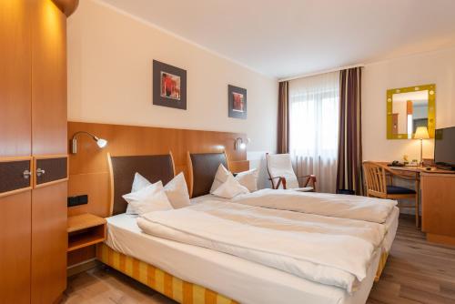 a hotel room with a large bed and a desk at Avenon Privathotel Schwaiger Hof in Schwaig bei Nürnberg