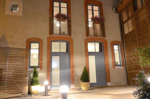 a facade of a building with windows and potted plants at Le Clos des Salins in Toulouse