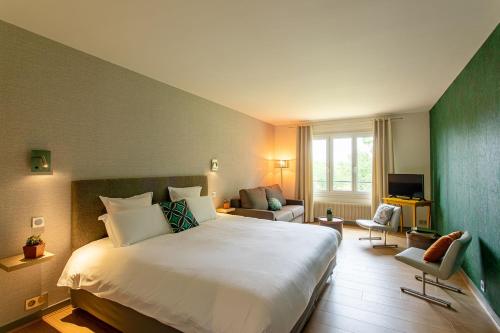 a bedroom with a large bed and a living room at Hôtel Restaurant Gastronomique La Huchette in Mâcon