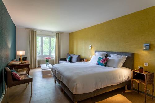 a bedroom with a large bed and a couch at Hôtel Restaurant Gastronomique La Huchette in Mâcon