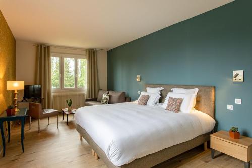 a bedroom with a large white bed and a blue wall at Hôtel Restaurant Gastronomique La Huchette in Mâcon