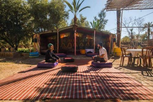 a man and woman sitting on pillows on the ground at Eco-Ferme Tamalait Skoura in Skoura