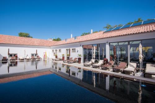 a swimming pool with lounge chairs and a house at Vila Gale Collection Elvas in Elvas