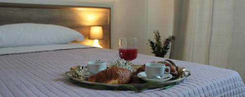 bandeja de comida en la cama con una copa de vino en Mansio Residence & Hotel en Elmas
