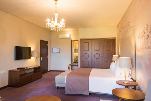 a bedroom with a bed and a television and a chandelier at Vila Gale Collection Elvas in Elvas