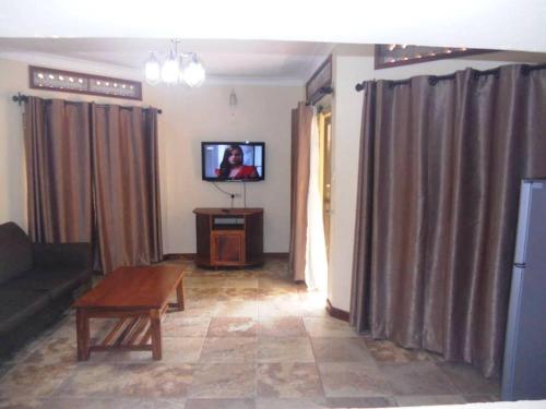 a living room with a couch and a table and a tv at Mt Moroto Hotel in Moroto