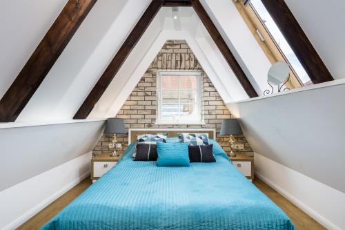 a bedroom with a blue bed in a attic at Elite Apartments Old Town Straganiarska in Gdańsk