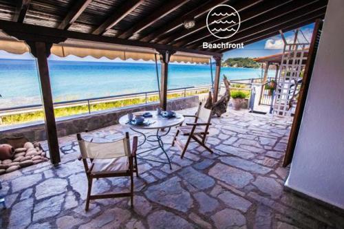 a patio with a table and chairs and the ocean at Houseloft Grand Sunset Siviri Beach in Siviri